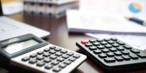 Calculator and laptop on a desk for tax management.